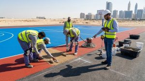 فرسان العمل السريع | الشركة الرائدة في إنشاء وتركيب جميع أنواع الملاعب الرياضية بجودة عالمية 3 sports flooring installation team applying EPDM and acrylic layers on a multi-sport court